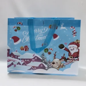 Sac cadeau de Noël bleu avec Père Noël, cerf et son village